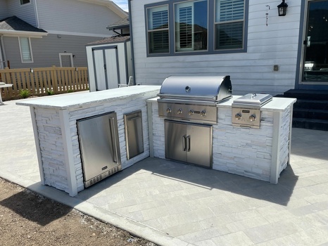 l shaped outdoor kitchen with dual burner and refrigerator and double access doors in stacked stone chalk finish-1