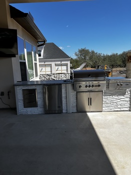 linear grill island with dual burner and refrigerator on patio in stacked stone chalk finish