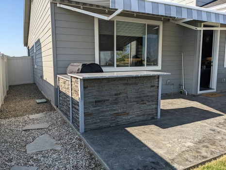 l shaped grill island with coyote grill cover on pation in stacked stone graphite finish-1