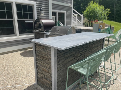 l shaped grill island with pizza oven and bar seating on patio in stacked stone graphite finish-1