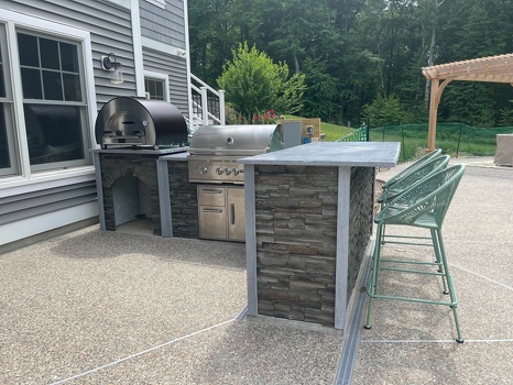 l shaped grill island with pizza oven and bar seating on patio in stacked stone graphite finish-2