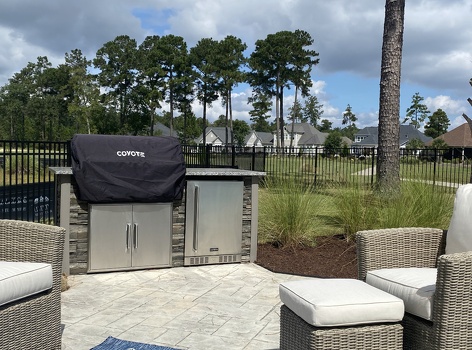linear grill island with refrigerator on paito with coyote appliance cover in stacked stone graphite finish