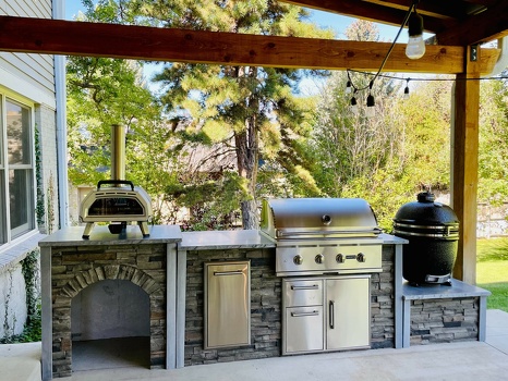 linear outdoor kitchen with pizza oven add on and asado stand add on in stacked stone graphite finish on patio-1