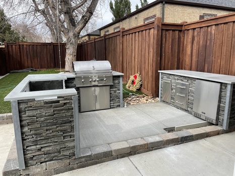 outdoor kitchen with storage pull out trash and refrigerator on patio in stacked stone graphite finish-1
