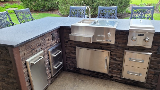 refreshment center dual burner and storage doors and drawers on l shaped grill island in stacked stone terra finish